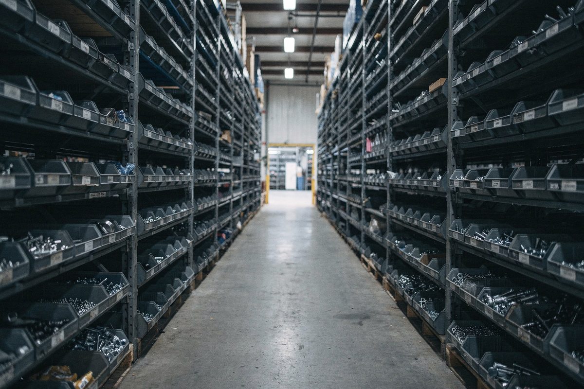 A warehouse aisle of shelving and labelled parts bins